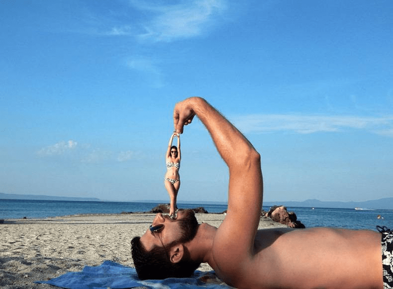 A person lying on the beach holding a fish

Description automatically generated with low confidence